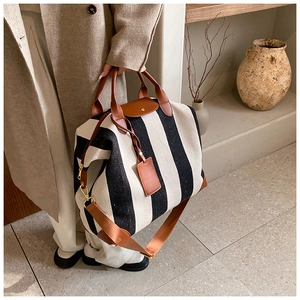 Détail du grand sac cabas rayé avec poignées en cuir marron et étiquette de bagage