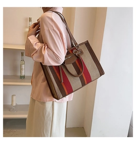 Gestreepte canvas shopper met leren bies getoond op model in een modern interieur