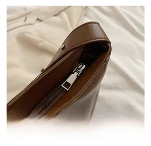 Detailed macro view of the smooth brown leather bag featuring a high-quality silver metal zipper