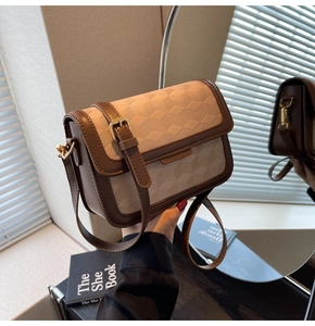 Detail of vintage square bag showing geometric texture, gold buckle and brown leather strap