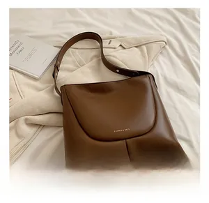 Detail of a dark brown leather shoulder bag with gold logo and pleated bottom design