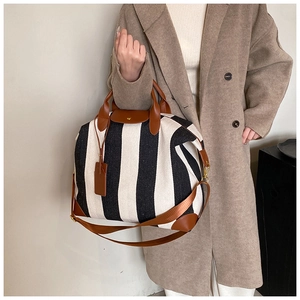 Détails d'un sac cabas à rayures avec finitions en cuir marron et bandoulière réglable