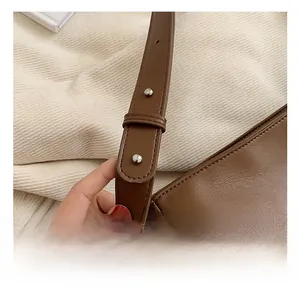 Close-up of adjustable strap detail on dark brown leather shoulder bag with silver buckle