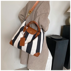Cabas en toile rayée noir et blanc avec accents en cuir marron porté à l'épaule
