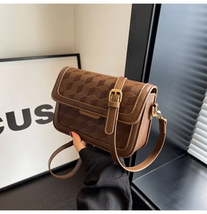 Detail view of the 3D geometric embossed texture on this dark brown leather crossbody bag