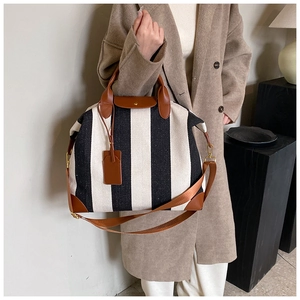 Détail du sac fourre-tout rayé avec poignées en cuir marron et bandoulière réglable