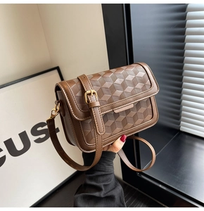 Detail showing brown crossbody bag with 3D geometric cube embossed texture and gold lock