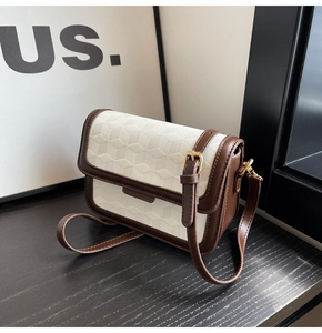 Detail of 3D geometric embossed leather crossbody bag with brown trim and gold hardware