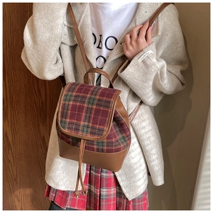 Detail of red and green plaid fabric and brown leather base on vintage backpack
