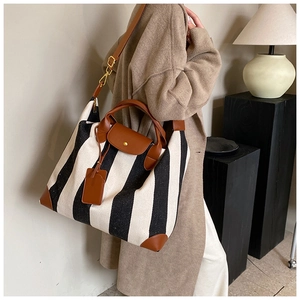 Détail du grand sac cabas rayé noir et blanc avec finitions élégantes en cuir marron