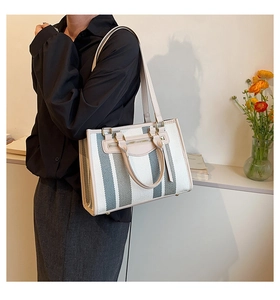 Detail of canvas tote bag with contrast vertical stripes and premium leather trim details