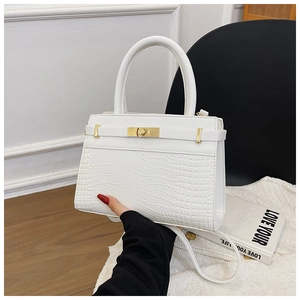 Detail of white crocodile pattern tote bag featuring golden twist lock and round handle