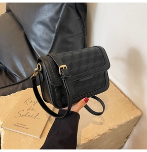 Detail shot of black crossbody square bag with 3D geometric embossed pattern texture