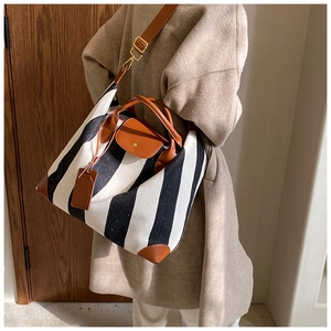 Détail du sac cabas en toile montrant le rabat en cuir marron et les rayures