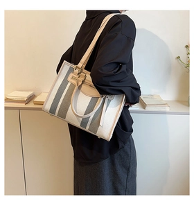 Minimalist canvas tote bag with green stripes shown worn by a model in a modern interior