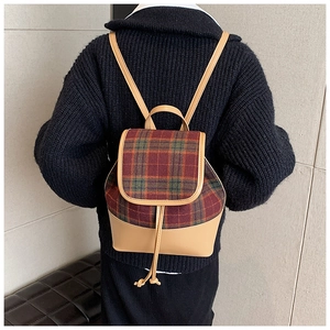 Rear view of a vintage plaid and khaki leather backpack styled on a black sweater
