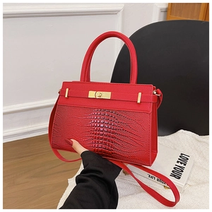 Detail of red croc-embossed leather handbag with gold ring hardware and textured finish