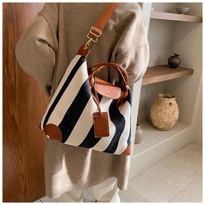Détail du grand sac cabas rayé avec bordures en cuir marron porté par un mannequin