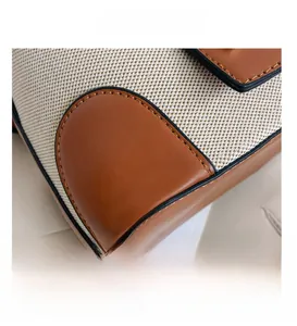 Detail view of cream canvas bucket bag with brown leather stitching and fine craftsmanship