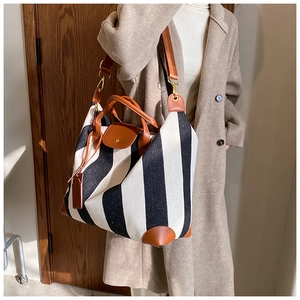 Détail d'un grand cabas en toile rayée avec lanières en cuir porté par un mannequin chic