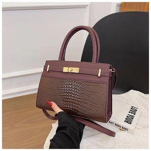 Detail of a deep purple and brown crocodile textured bag with a metal twist-lock