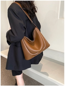 Brown leather large capacity hobo shoulder bag with adjustable strap worn by model