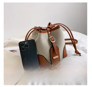 Detail presentation showing the size of the canvas bucket bag relative to a smartphone