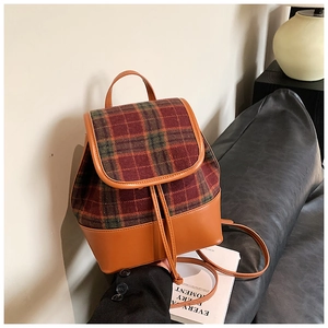 Detail view of retro plaid backpack with brown faux leather trim and drawstring closure