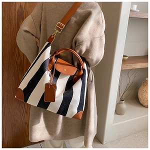 Détail d'un sac cabas en toile rayée noir et blanc avec finitions en cuir marron