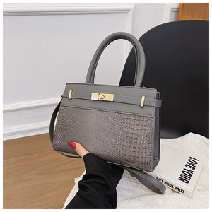 Detail of grey handbag with crocodile texture, lychee pattern, and gold twist lock
