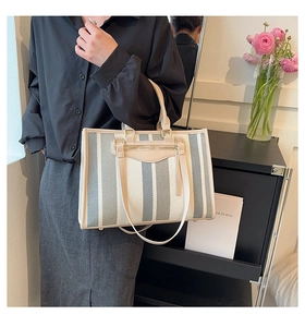 Detail of canvas tote bag with striped pattern, leather handles and protective base studs