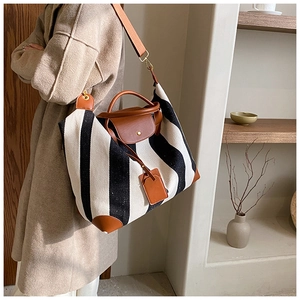 Détail du sac cabas en toile rayée noir et blanc avec poignées en cuir marron