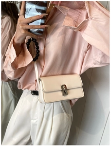 Cream crossbody saddle bag with golden H buckle shown on model in a mirror selfie