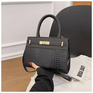 Close-up of black crocodile embossed leather handbag with gold metal twist lock detail