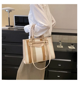 Detail of canvas tote bag showing striped weave and faux leather shoulder strap