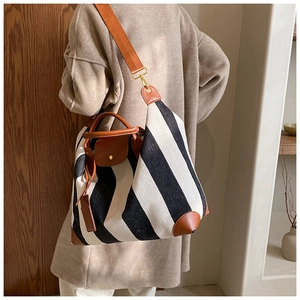 Détail d'un grand sac fourre-tout en toile rayée avec des poignées en cuir marron