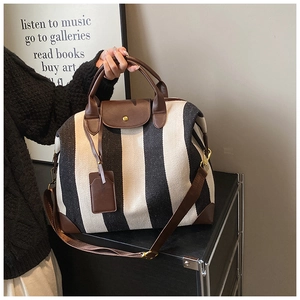 Détail du sac fourre-tout en toile rayée avec garniture en cuir brun et bandoulière