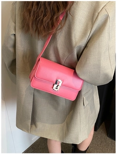 Pink saddle bag crossbody style with silver metal clasp worn on grey blazer