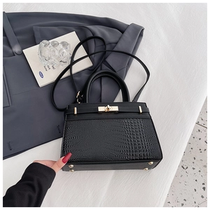 Close-up of black crocodile pattern leather texture with golden metal twist-lock buckle