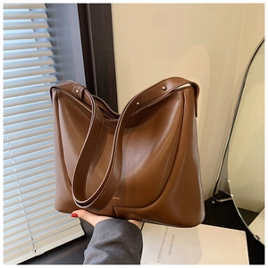 Close-up of the smooth brown faux leather texture and golden logo on a women's tote bag