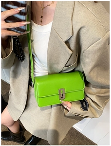 Detail of neon green crossbody bag featuring a unique silver razor blade metal clasp