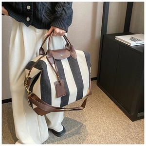 Détail du cabas en toile rayée avec poignées en cuir et bandoulière réglable