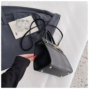 Detail view of the black crocodile pattern leather texture and gold metal twist lock