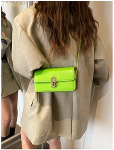 Close-up of a bright green rectangular leather saddle bag with a metallic clasp detail