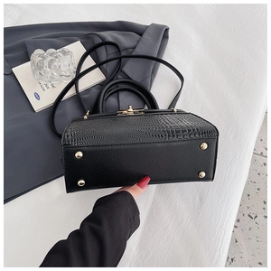 Detail of crocodile embossed leather texture and golden metal twist lock on black bag