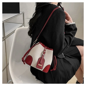 Detail of red and cream canvas bucket bag with leather trim and drawstring closure