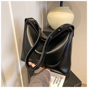 Macro detail of glossy black PU leather shoulder bag featuring gold fashion lettering