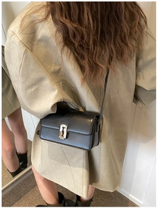 Detail of a black leather saddle bag with a unique silver razor blade metal buckle
