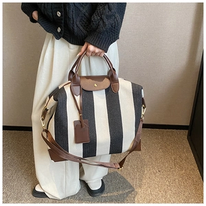 Détail d'un sac cabas rayé avec poignées en cuir marron et bandoulière réglable pratique