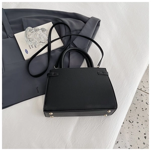 Top view of black trapezoid leather bag with gold protective base studs and top handles